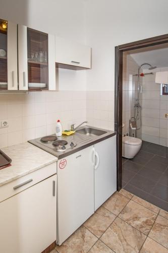 a white kitchen with a sink and a bathroom at Bed & Breakfast Villa Anita in Medulin