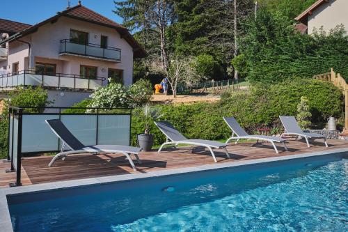 - une piscine avec des chaises longues à côté d'une maison dans l'établissement L'Orée de la Chambotte, à Chindrieux