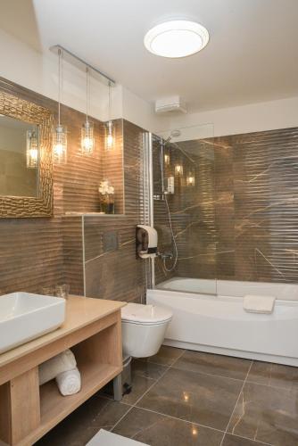 a bathroom with a tub and a toilet and a sink at Hotel Meduza in Senj