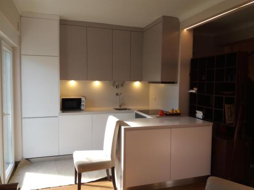 a kitchen with white cabinets and a chair and a microwave at Traditional Villa In S Pedro , ESTORIL in Alapraia
