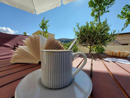 a coffee cup sitting on a table with a book at Theasis Athens in Athens