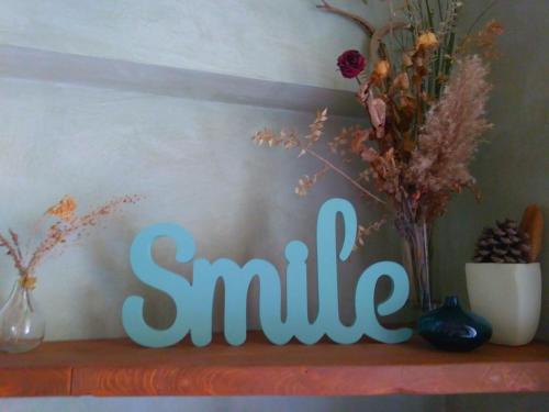 a sign that says smile sitting on a shelf with flowers at Folia in Rome