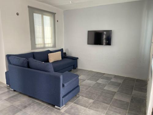 a blue couch in a living room with a tv at Casa con Piscina en Chixchulub a 100 m de la playa in Chicxulub