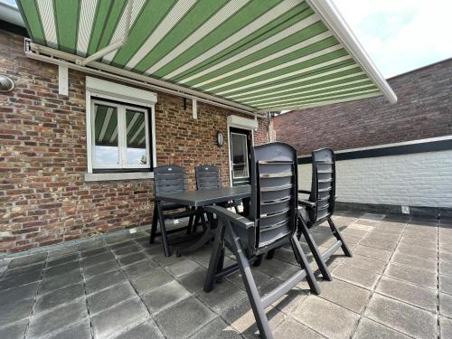 a table and chairs on a patio with awning at Vakantieappartement Diepstraat in Eijsden