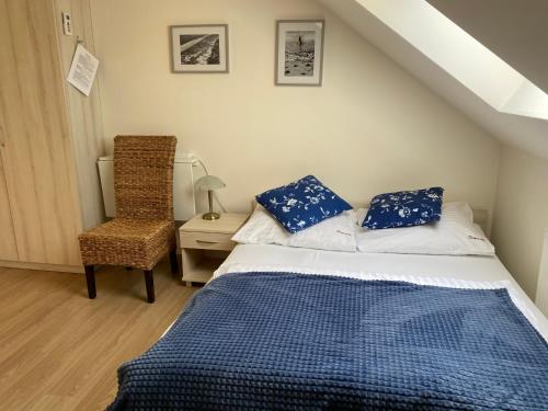 a bedroom with a bed with blue pillows and a chair at Villa Słoneczko in Wisełka