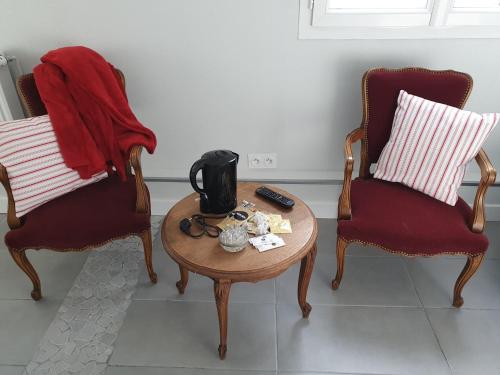 a living room with two chairs and a coffee table at Hôtel restaurant du Commerce in Poulainville