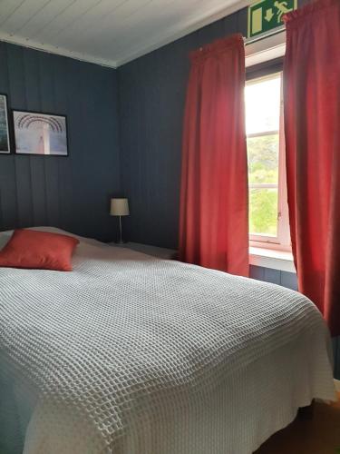 een slaapkamer met een bed en een raam met rode gordijnen bij Sjøhaug Rorbu in Moskenes