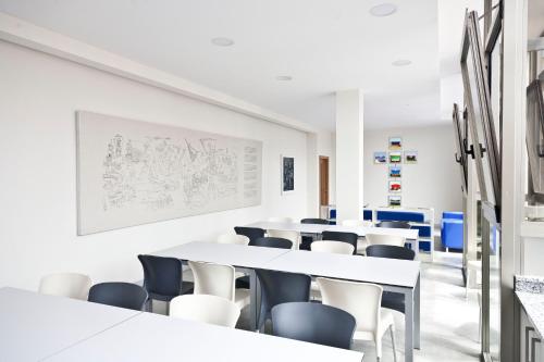 a room with tables and chairs in a classroom at Albergue Bela Muxia in Muxia