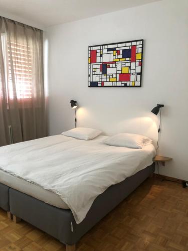 a bedroom with a bed with a painting on the wall at Central 2 bedroom flat in heart of Eaux-vives in Geneva