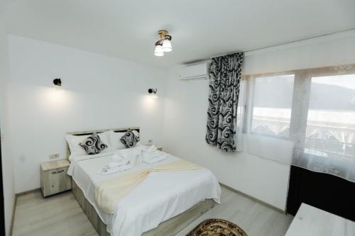 ein weißes Schlafzimmer mit einem Bett und einem Fenster in der Unterkunft Pensiunea Bellavista in Dubova