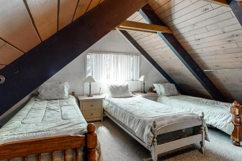 a attic bedroom with two beds and a window at Snowpeak Chalet in Camp Connell