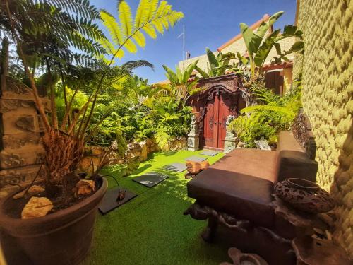 a garden with plants and a red door at Villa Paraiso - Naturism Optional Adults Only in Porches