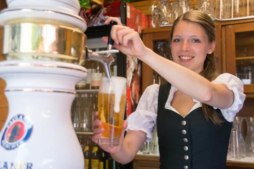 Eine Frau hält ein Glas Bier. in der Unterkunft Gasthof Diem in Krumbach