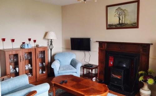 ein Wohnzimmer mit einem Sofa, Stühlen und einem Kamin in der Unterkunft Bridgeview Farmhouse Bed and Breakfast in Kilbrittain
