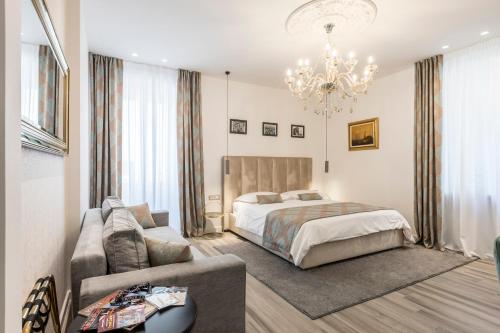 een slaapkamer met een bed, een bank en een kroonluchter bij Elixir luxury rooms in Split