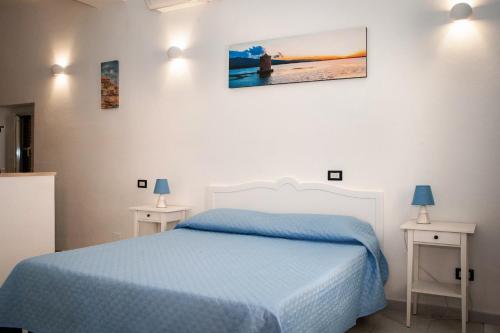 um quarto com uma cama azul e duas mesas em B&B La Pineta em Orbetello