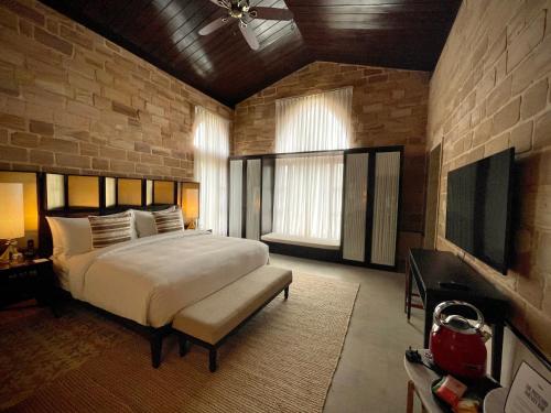 a bedroom with a large bed and a tv at The Postcard Gir Wildlife Sanctuary in Sasan Gir