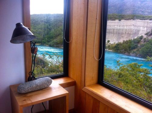 a room with two windows with a view of a river at Lodge BordeBaker in Puerto Bertrand