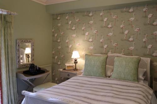 a room with a bed, lamps, and a painting on the wall at Rafters at Riverside House Hotel in Bakewell