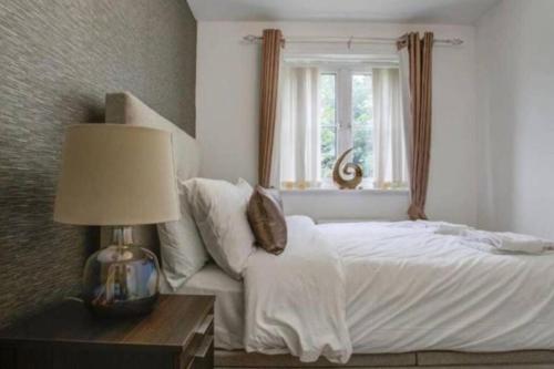 Luxury 4 Bedroom House في مانشستر: غرفة نوم بسرير ومصباح ونافذة