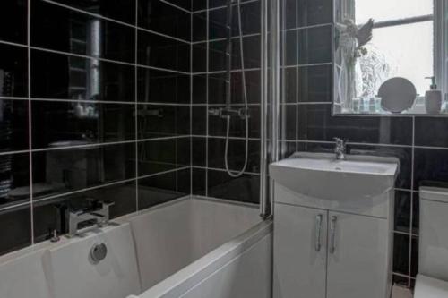 a bathroom with a bath tub and a sink at Luxury 4 Bedroom House in Manchester