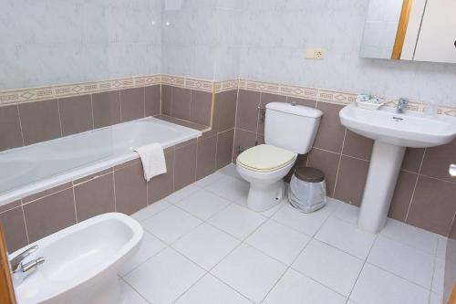 een badkamer met een toilet, een wastafel en een bad bij Pensión Felipe in Carboneras