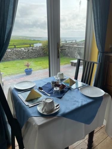 a table with a blue table cloth and a window at Cois Farraige in Lahinch