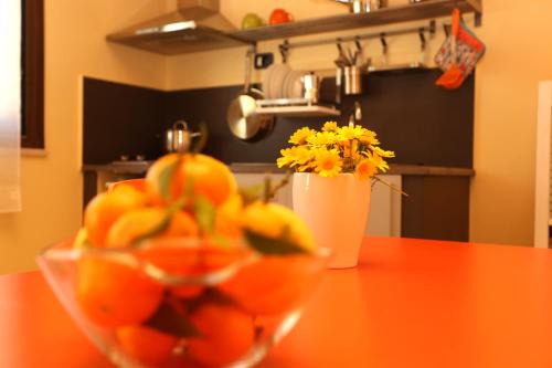 eine Schüssel Orangen auf dem Tisch mit einer Vase Blumen in der Unterkunft Cuore Della Valle in Cefalú