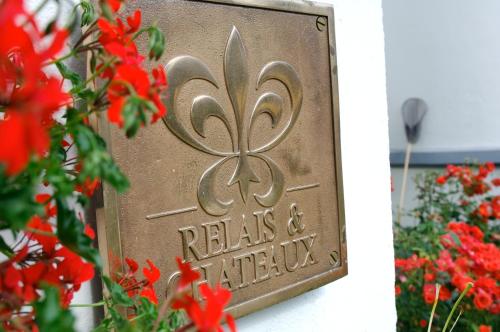 a metal sign on a wall with red flowers at Hôtel de la Plage in Plonévez-Porzay