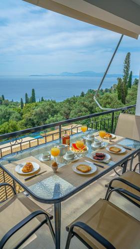 a table with plates of food on a balcony at Apartment Zeus with private pool and sea view in Nisakion