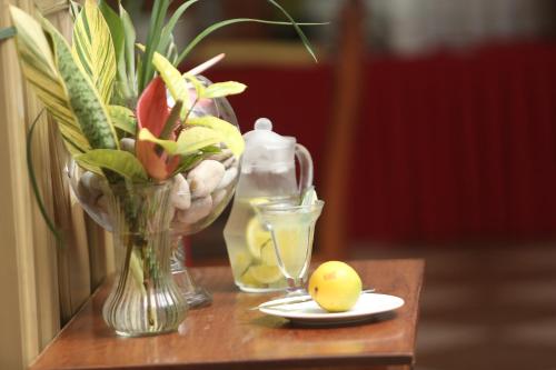 a table with a vase of flowers and a plate with a lemon at Adden Palace Hotel & Conference Centre in Mwanza