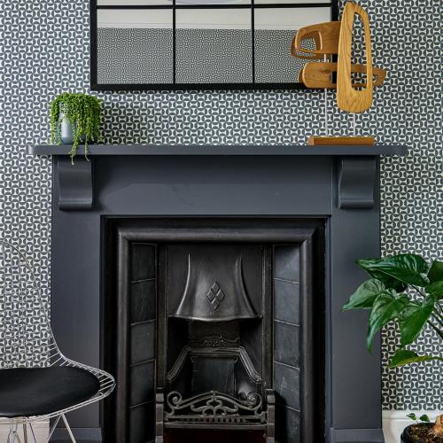 a black fireplace with a chair and a mirror at Townhouse Exeter in Exeter