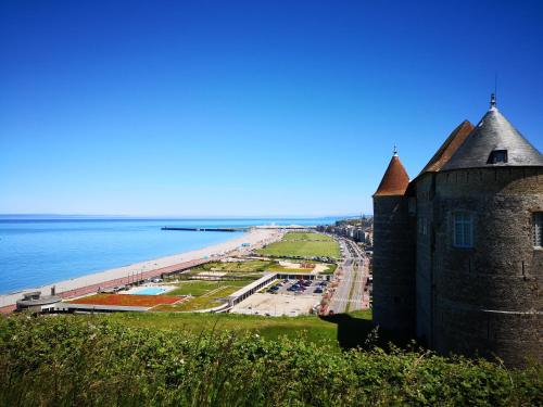 an old castle on a hill next to a beach at Contre vents et marées in Mesnil-Val-Plage