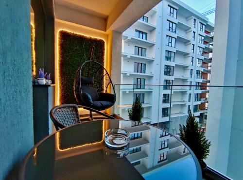 einen Glastisch und Stühle auf einem Balkon mit einem Gebäude in der Unterkunft Primera Residence Mamaia Nord in Mamaia Nord – Năvodari