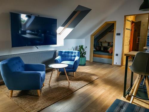 a living room with two blue chairs and a table at Tűztorony apartman in Veszprém