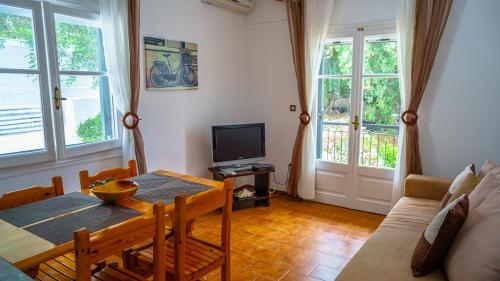 a living room with a dining room table and a television at Apartment Zeus with private pool and sea view in Nisakion