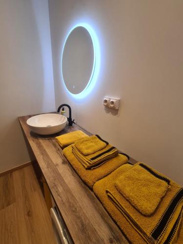 uma casa de banho com lavatório, espelho e toalhas em Appart plein centre lit King size et canapé lit em Barcelonnette