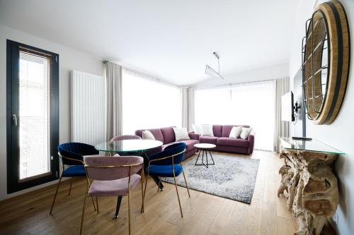 salon z fioletową kanapą, stołem i krzesłami w obiekcie Aparthotel Inspire Miodova Residence w Krakowie