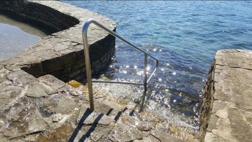 a metal hand rail in the water next to the ocean at Alba Sanja i Teran in Funtana
