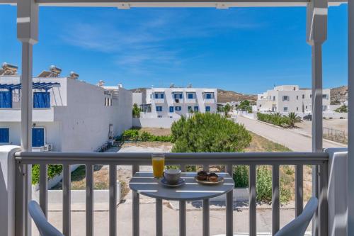 a table on a balcony with a view of a street at Orama Milos in Adamas