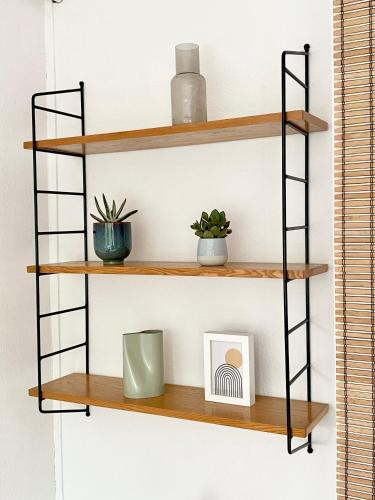 a shelf with two plants and a clock on it at Napsugár Retro Apartman in Gárdony