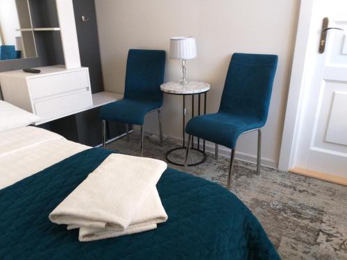 a bedroom with two blue chairs and a bed and a desk at Apartamenty i pokoje gościnne KOŁODZIEJÓWKA in Sandomierz