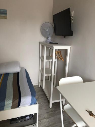Cette chambre comprend un lit, une télévision et une table. dans l'établissement Joli studio meublé proche de la plage, à Veules-les-Roses