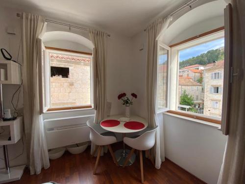 een kleine tafel en stoelen in een kamer met een raam bij Apartman Torre in Hvar