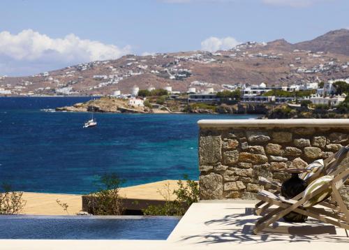 a bench sitting on top of a stone wall next to the ocean at Bonzoe Suites & Villas in Mýkonos City