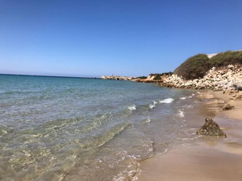 una spiaggia con una roccia in acqua di paradiso camper a Pachino
