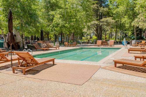 a pool with wooden benches and tables and trees at PlumpJack Inn in Olympic Valley