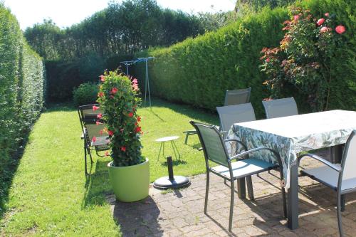 a garden with a table and chairs and a potted plant at "Mi-a-clo" in Cucq