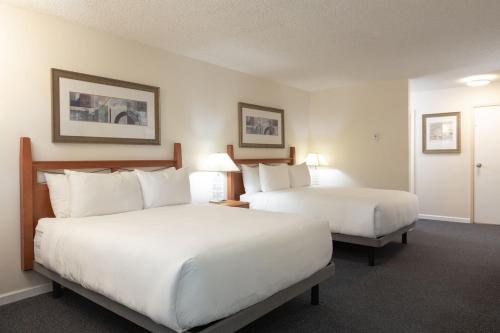 a hotel room with two beds and two lamps at Robin Hood Inn and Suites in Victoria