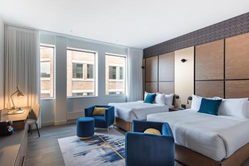 a hotel room with two beds and a desk and chairs at Hotel Royal William, an Ascend Collection Hotel in Quebec City